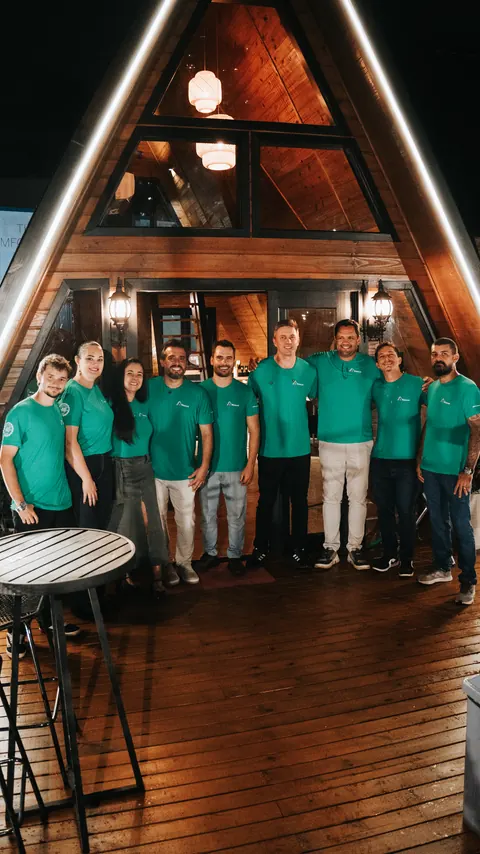 Equipe reunida em frente a um chalé A-frame 321 Modular